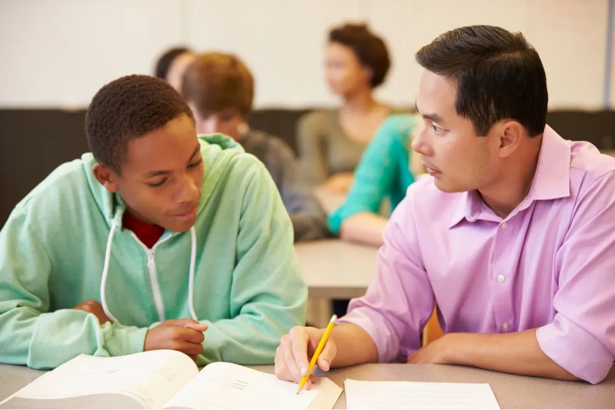 A tutor and a student working through a problem together at a desk