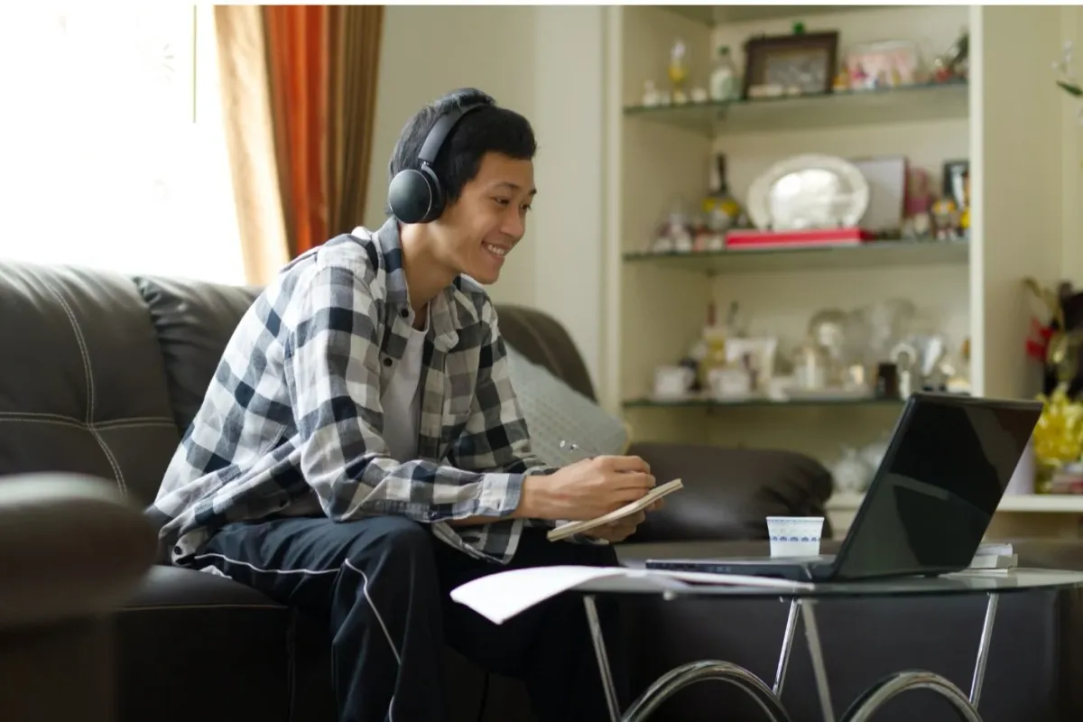 A student in headphones at a laptop in a tutoring session at home