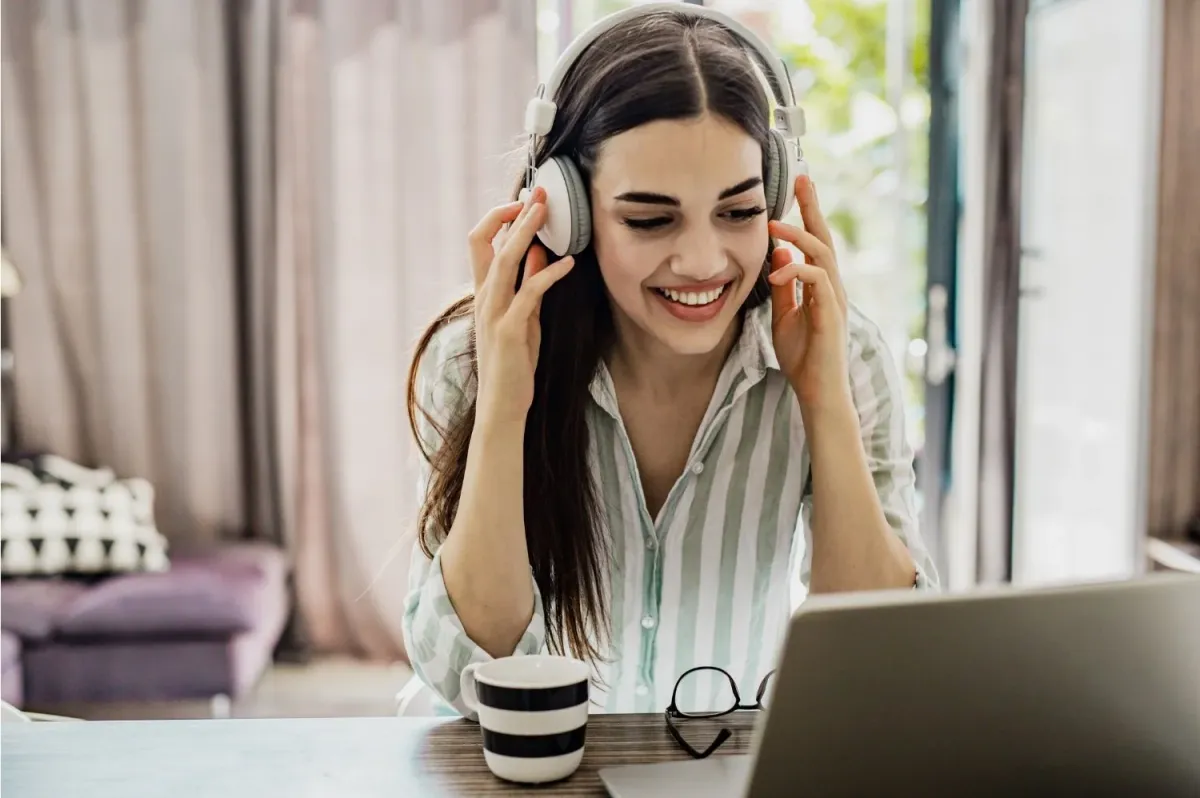 A student smiling in headphones during an online tutoring session
